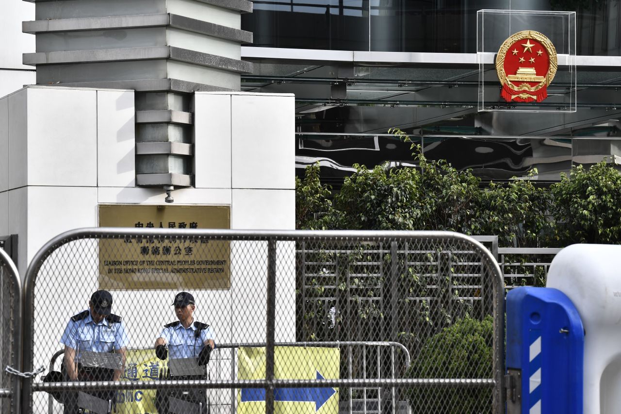 Police officers stand guard next to China's liaison office emblem being protected by plexiglass during a demonstration in Hong Kong on July 28, 2019. 