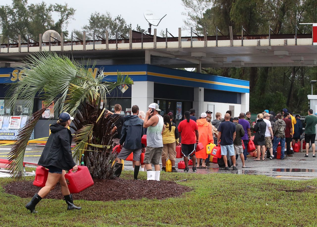 People wait in line to fill up their gas cans at a gas station that was damaged when Hurricane Florence hit the area, on September 15, 2018 in Wilmington, North Carolina.