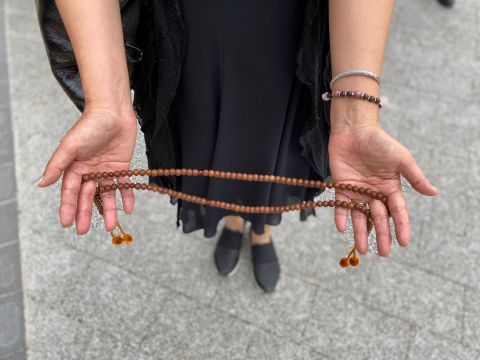 Naomi Aoki, a mourner in Tokyo, brought Buddhist beads as she waited for the hearse to pass by on July 12.
