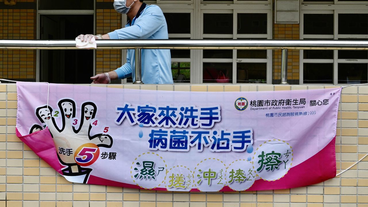 A man wears a face mask while cleaning a handrail above a sign telling students how to wash their hands at a middle school in Taoyuan, Taiwan on February 29.