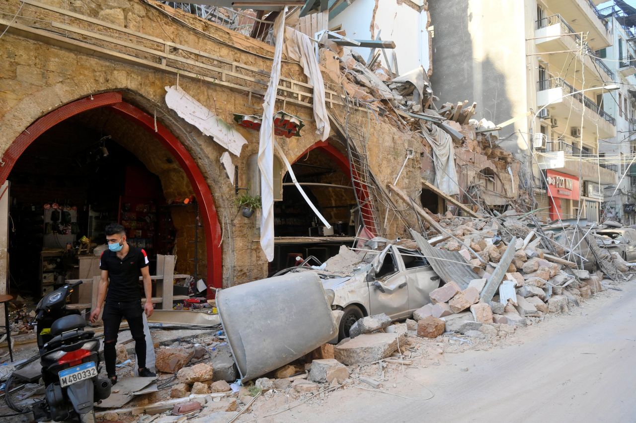 A person stands by damaged buildings and vehicles on August 5.