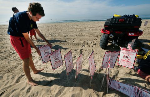 Huntington Beach lifeguards prepare signs warning people that contact with the water may cause illness, as they close the beach after an oil spill in Huntington Beach, California on October 3.