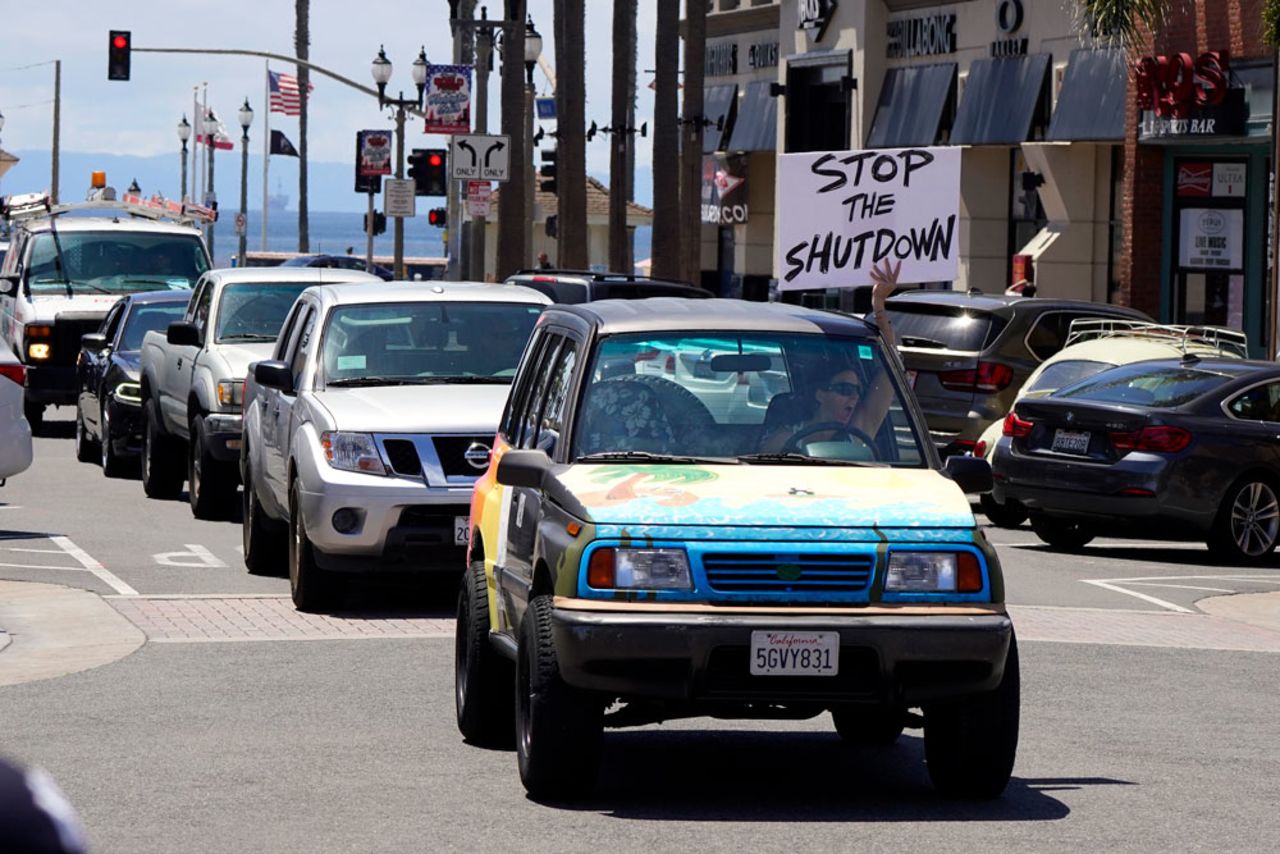 A driver waves a sign at other protesters who were demonstrating against stay-at-home orders that were put in place due to the coronavirus outbreak on Friday, April 17, in Huntington Beach, Calif.