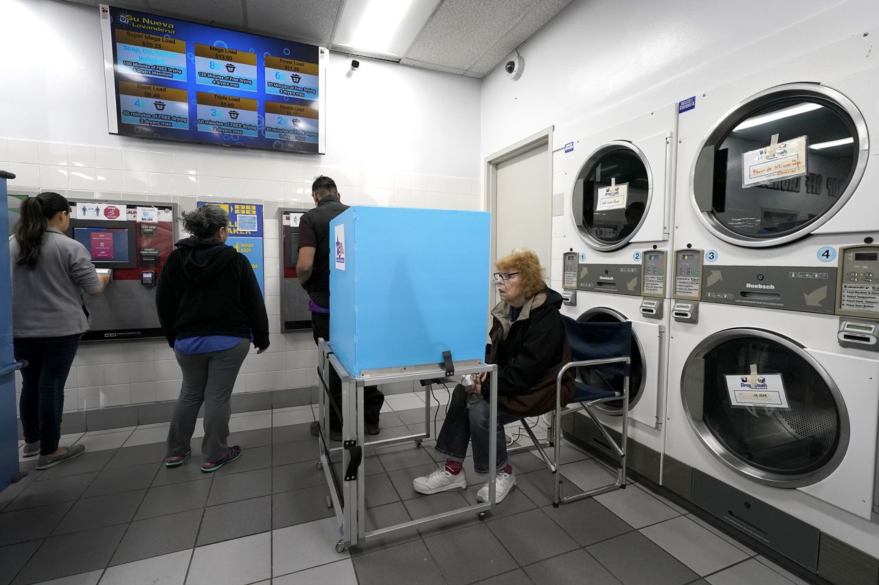 Jeanette Buchanan works on her electronic ballot as patrons at the Su Nueva Lavanderia put cash on laundry cards near Chicago's Midway Airport Tuesday. (AP Photo/Charles Rex Arbogast)