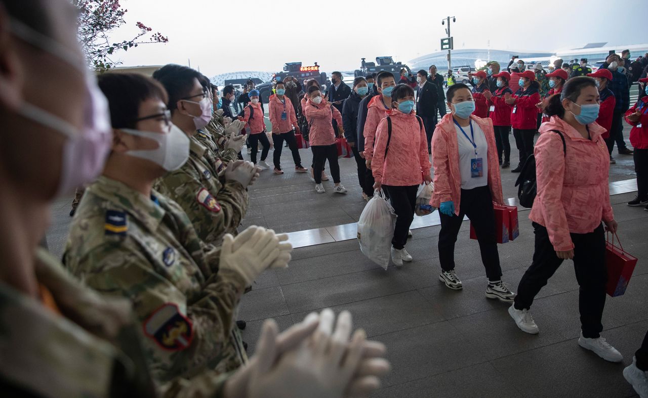 In this March 18 photo released by China's Xinhua News Agency, people applaud as departing medical workers enter Wuhan Tianhe International Airport in Wuhan in central China's Hubei Province. 