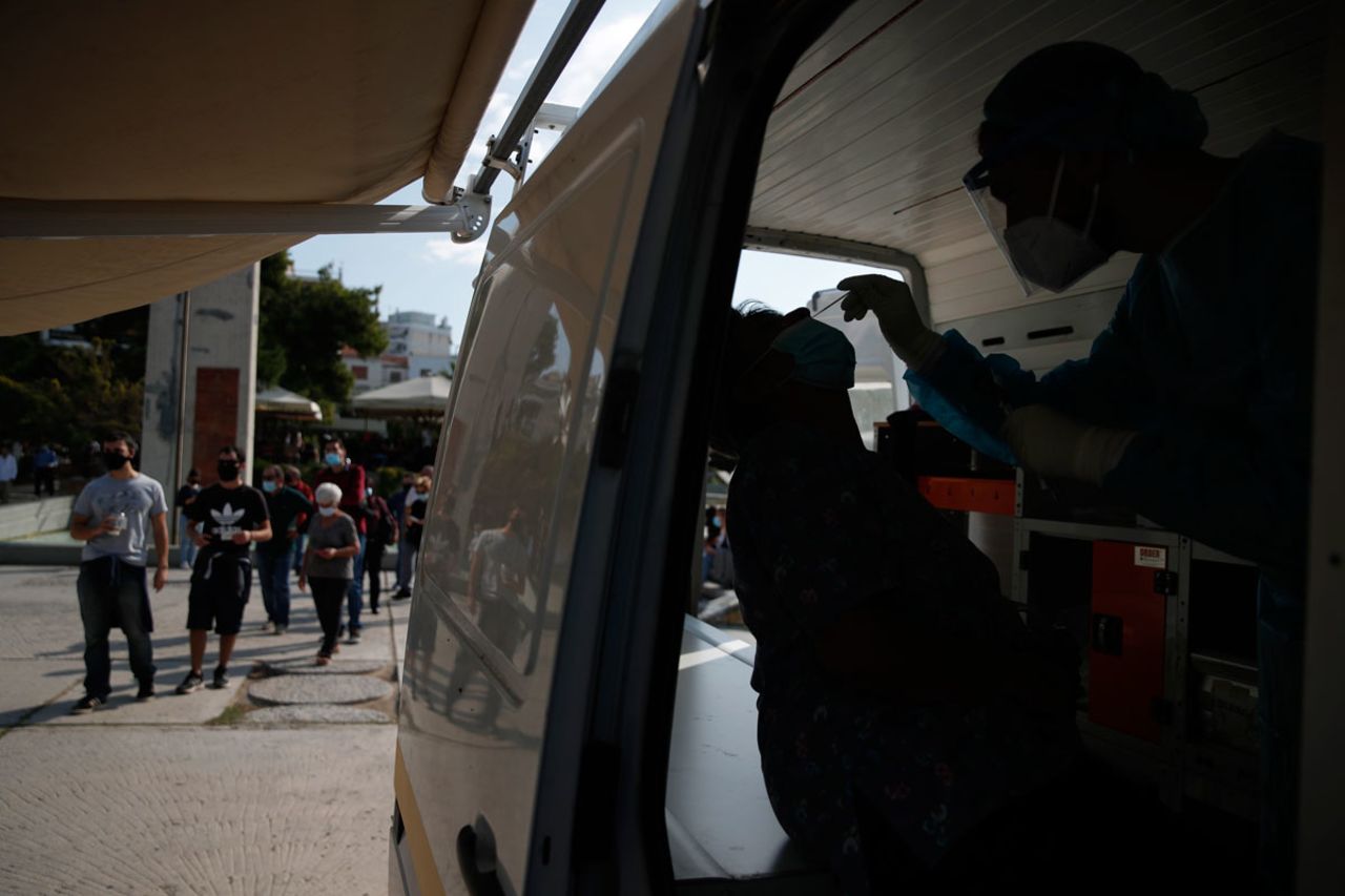 A medical worker collects a swab from a commuter during rapid tests for COVID-19 at a suburb in Athens, on October 22.