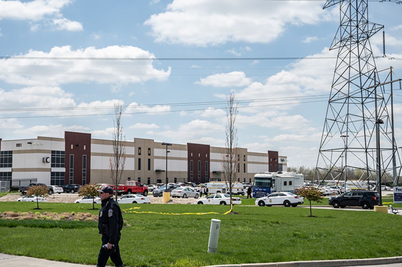 A police officer walks on the sidewalk near the crime scene in the parking lot of a FedEx Ground facility on April 16, in Indianapolis, Indiana. 