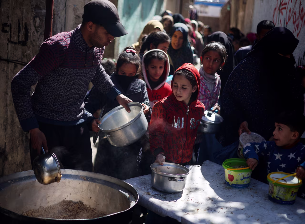 Palestinian children wait to receive food cooked by a charity kitchen amid shortages of food supplies, in Rafah, Gaza, on March 5. 