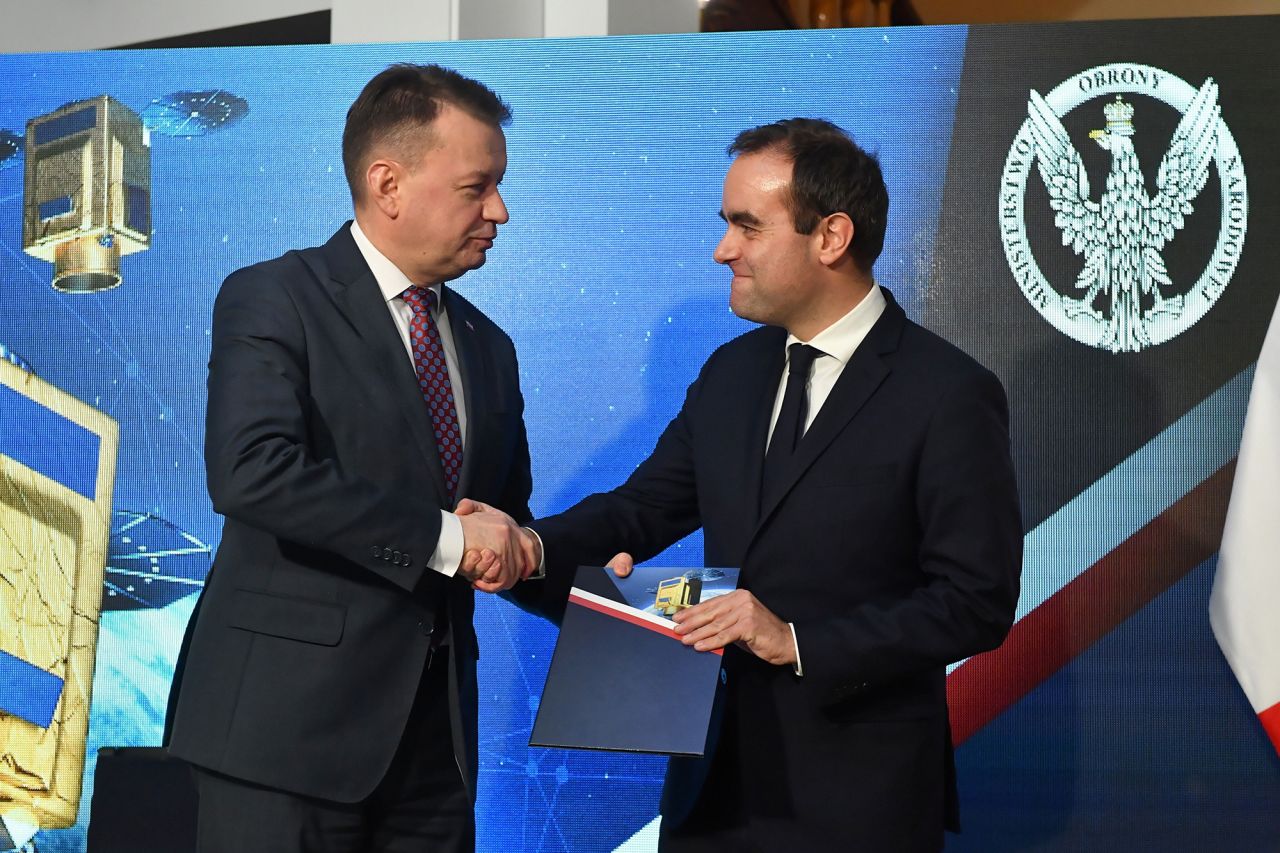 Polish Defense Minister Mariusz Blaszczak, left, and French Defense Minister Sebastien Lecornu shake hands during the signing of a contract for the sale of French satellites to Poland in Warsaw, on November 27.