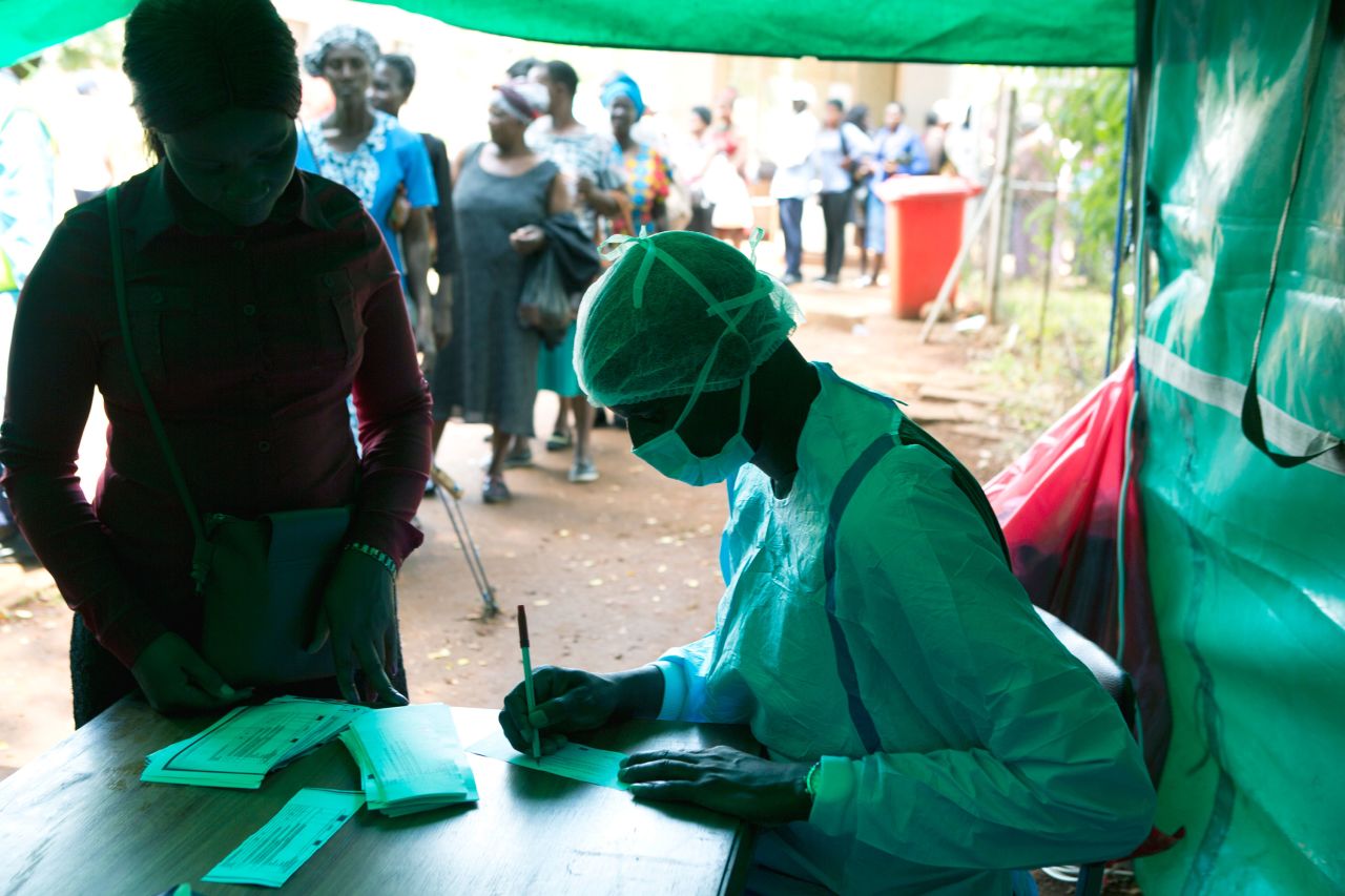 People wait in a queue to have their temperatures taken by health workers before entering a public hospital, in Harare, Zimbabwe, Saturday, March 21, 2020. (AP Photo/Tsvangirayi Mukwazhi)