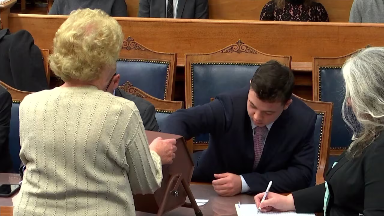 Rittenhouse reaches into the tumbler to pull out a juror number on Tuesday.