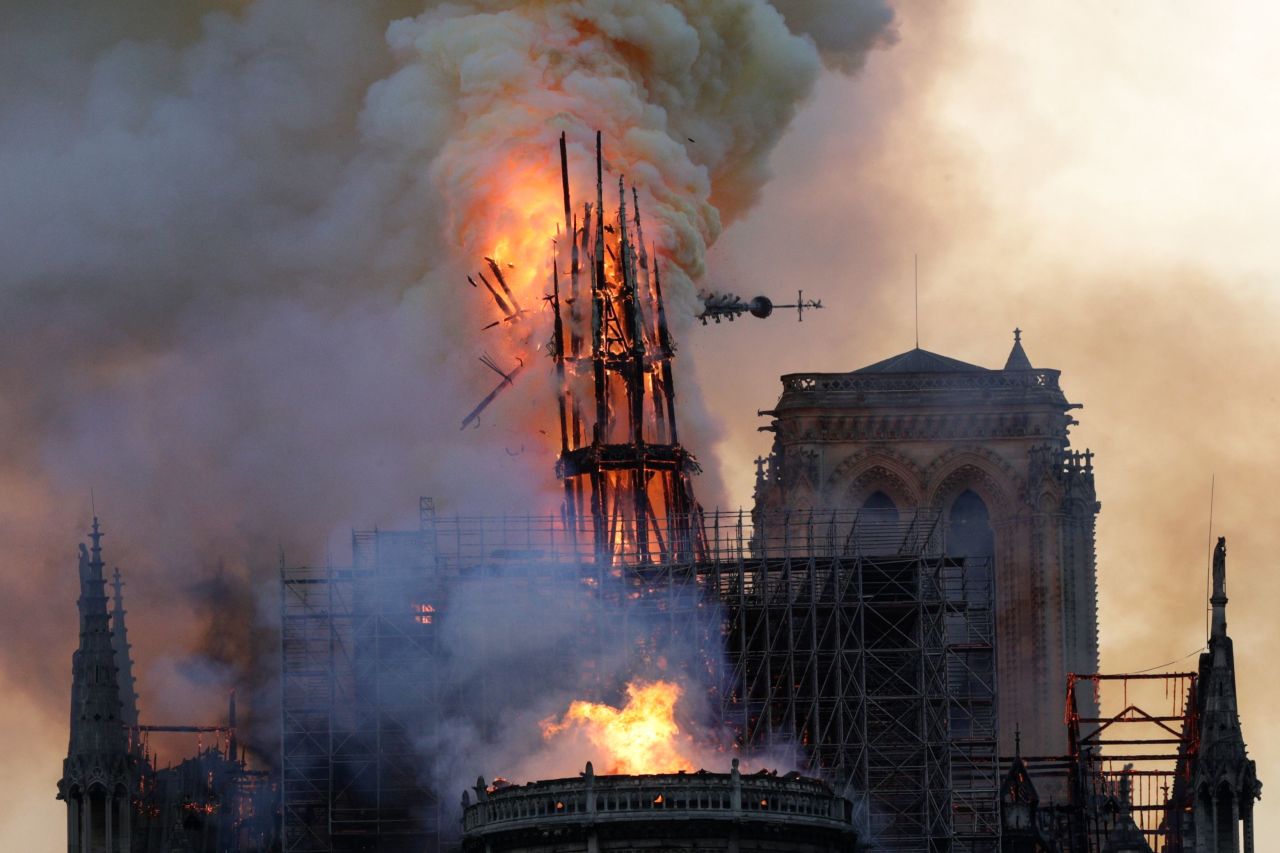 The spire collapses as smoke and flames engulf Notre Dame Cathedral in Paris.