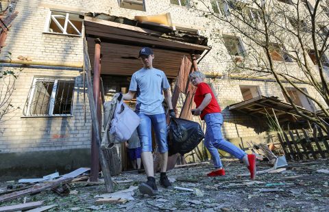 People clean up outside a damaged residential building located in in Donetsk, Ukraine, on June 20.