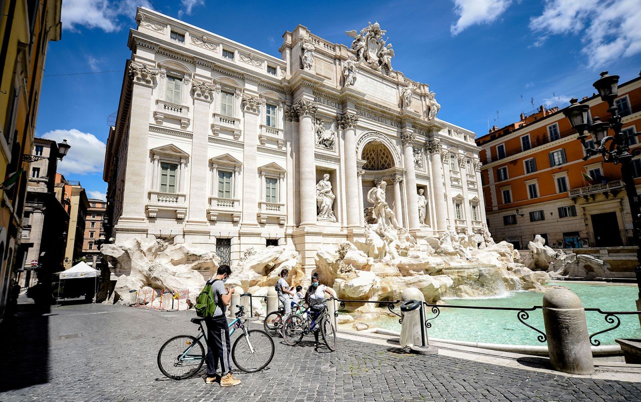 A family rides bicycles near Trevi Fountain empty of tourists during the Covid-19 pandemic in Rome on May 3.