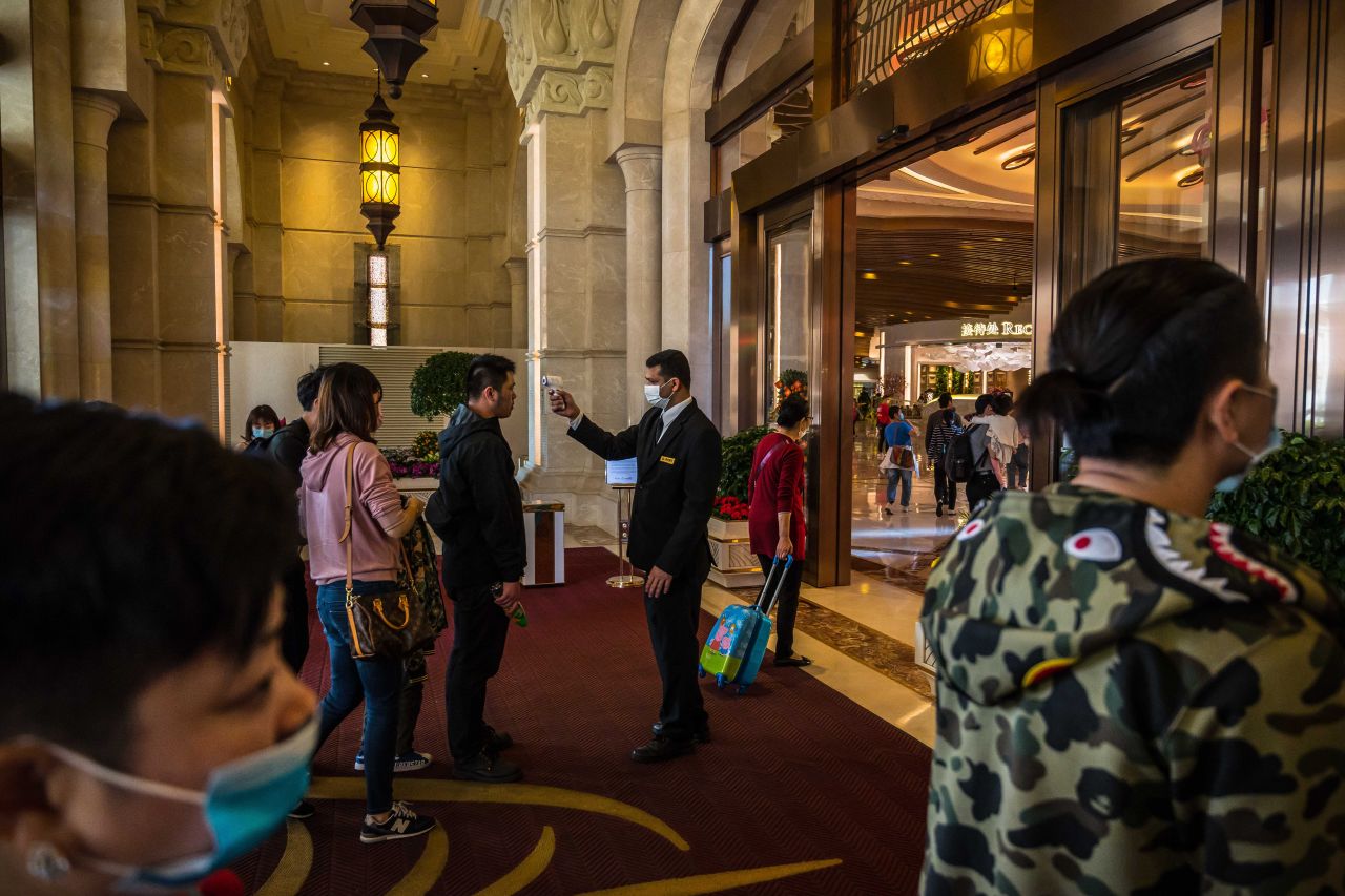 An attendant checks the temperature of a tourist at the entrance to the Galaxy Macau casino and hotel in Macau, China, on Friday, January 24.