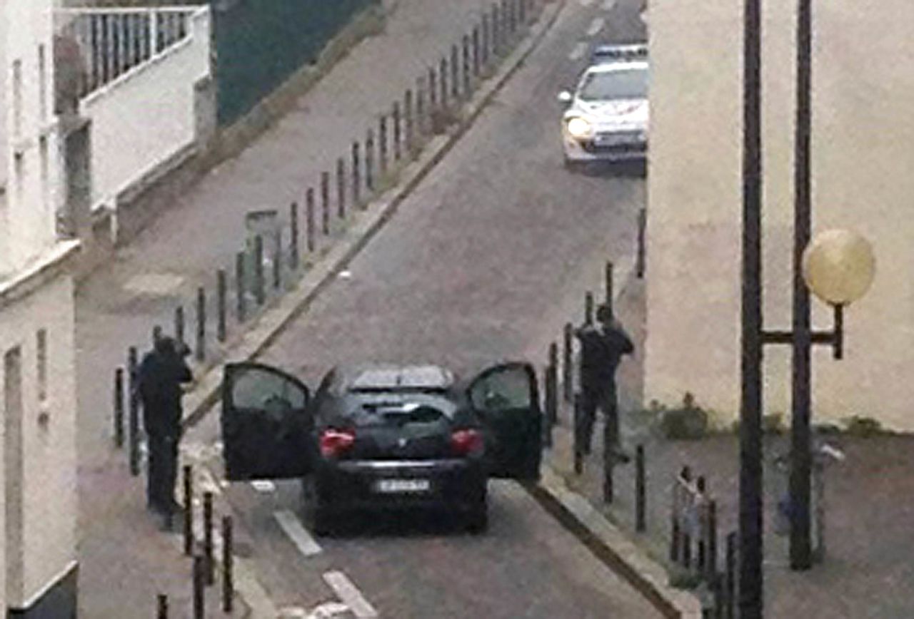 Armed gunmen face police officers near the offices of the French satirical newspaper Charlie Hebdo during the attack in Paris, on January 7, 2015.