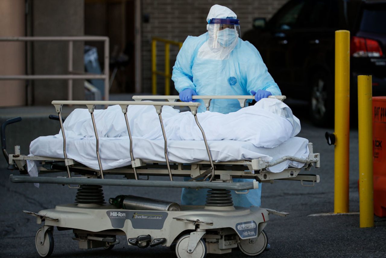 A medical worker wearing personal protective equipment wheels a body to a refrigerated trailer serving as a makeshift morgue at Wyckoff Heights Medical Center on Monday, April 6, in the Brooklyn borough of New York. 