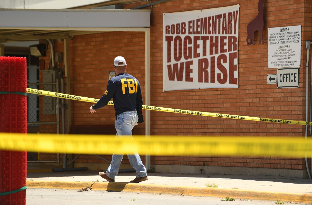 An FBI agent walks by the outside of Robb Elementary School in Uvalde, Texas on May 25, one day after the school shooting. 