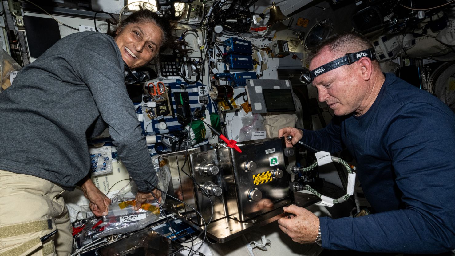 NASA's Boeing Crew Flight Test astronauts Suni Williams (left) and Butch Wilmore, now members of the SpaceX Crew-9 mission, are shown in June preparing orbital plumbing hardware for installation inside the International Space Station’s bathroom.