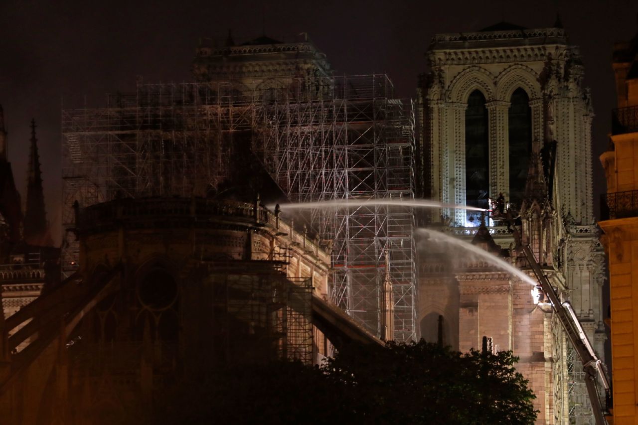 Firefighters are seen dousing the facade of the cathedral in the early hours of Tuesday. 