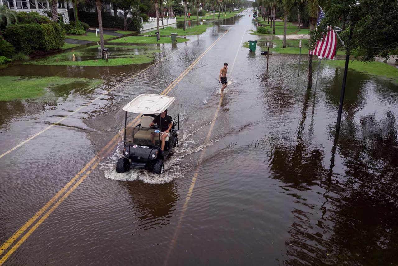 A man is pulled by a golf cart through flood water in Isle of Palms, South Carolina, on August 6. 