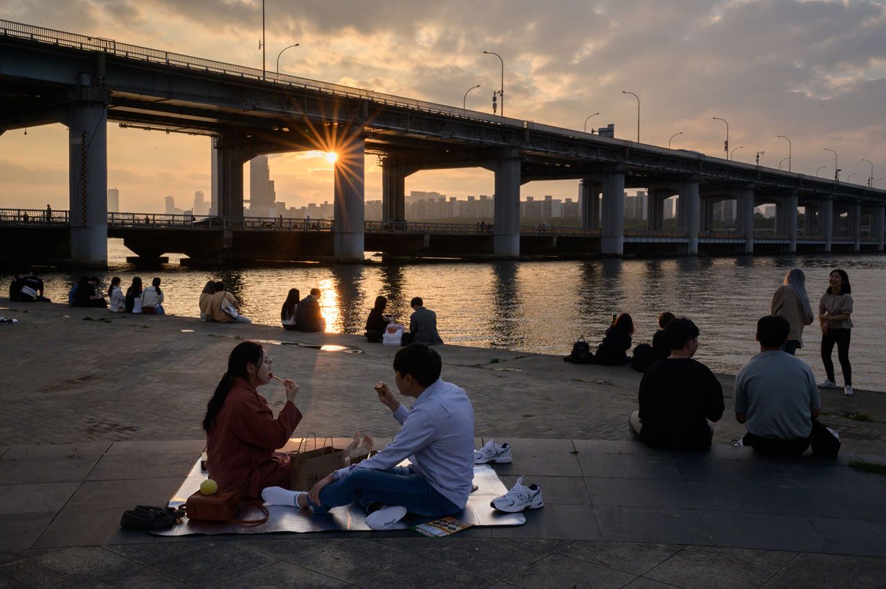 People sit before the city skyline and Han River in Seoul, South Korea, on May 24. 