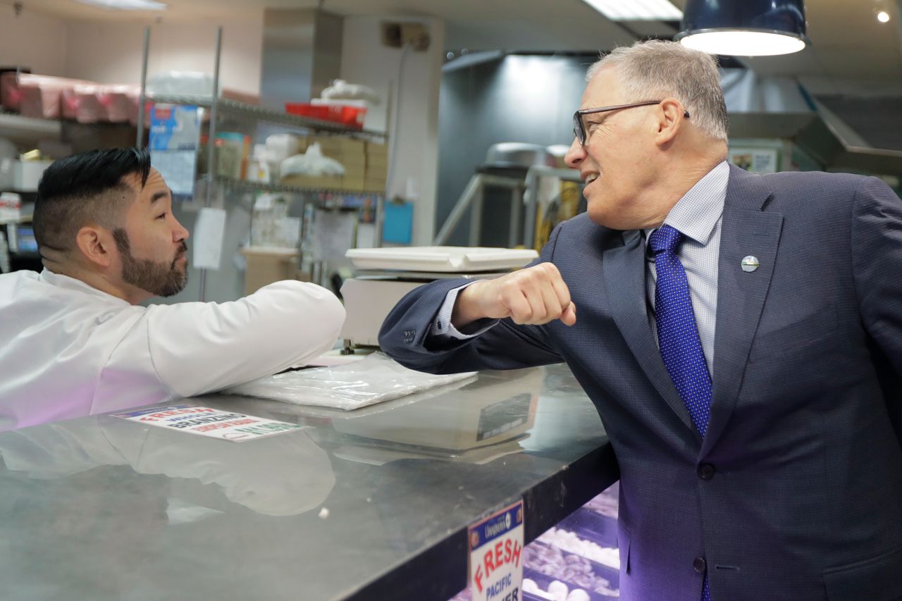 Washington Gov. Jay Inslee, right, bumps elbows with a worker at the seafood counter of the Uwajimaya Asian Food and Gift Market, Tuesday, March 3 in Seattle's International District.