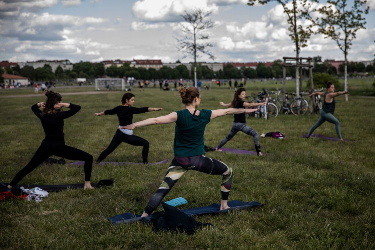 Group of "Yoga on the move" class participants practice Yoga in Tempelhofer Feld on May 17 in Berlin.