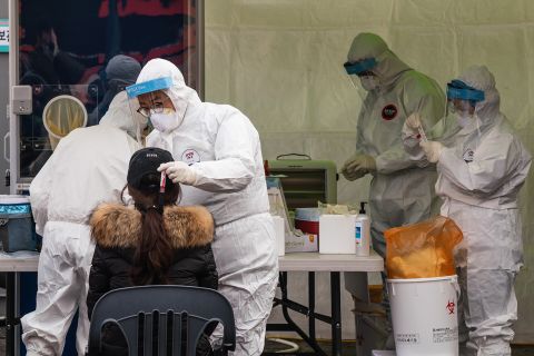 A healthcare worker collects samples from a woman at a temporary Covid-19 testing site in front of Seoul Station in South Korea, on December 18.