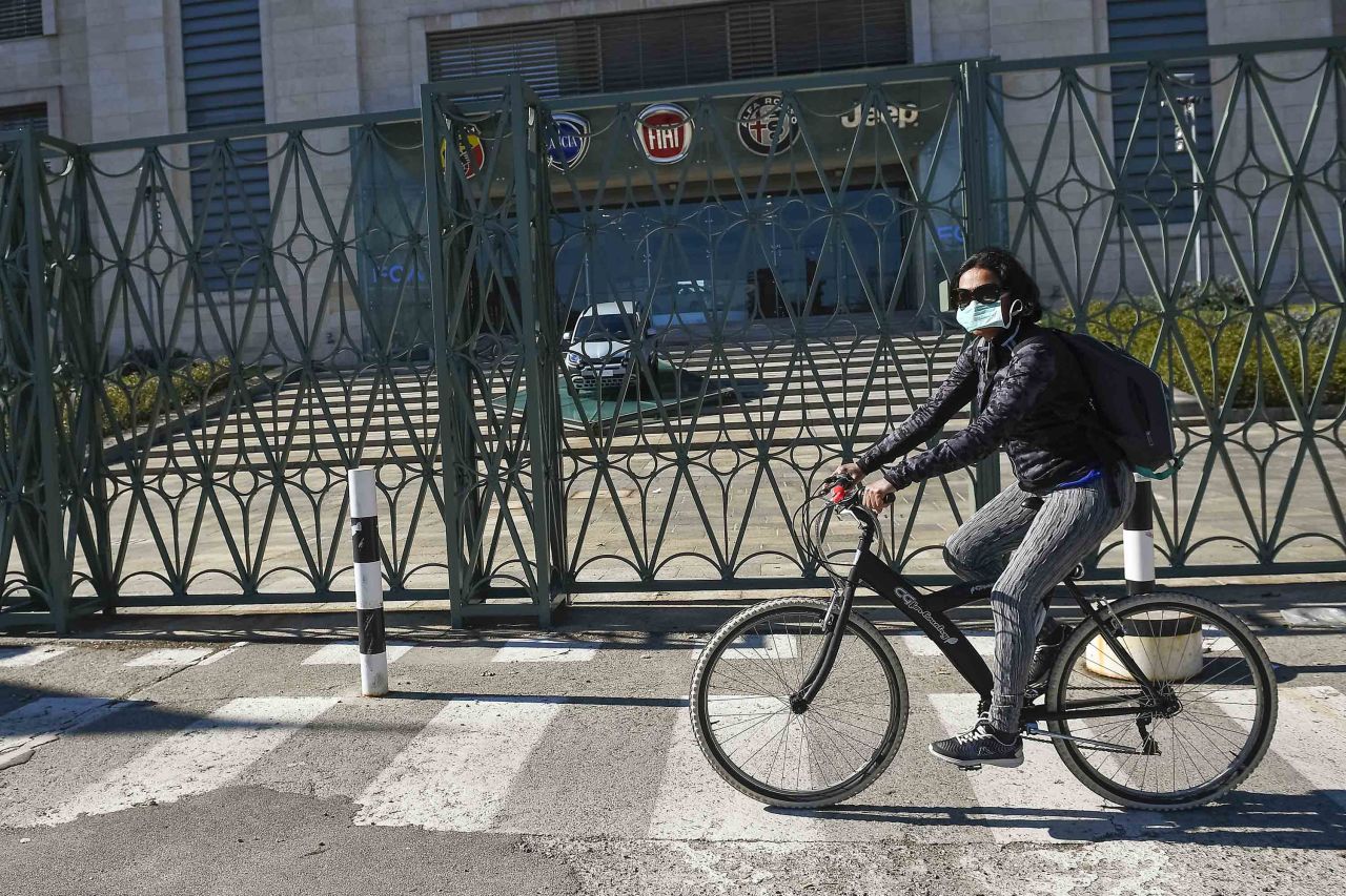 A cyclist wearing a respiratory mask rides past the Fiat Mirafiori plant in Turin, Italy, on March 11.