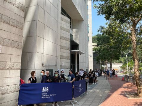 La gente si è messa in fila sotto il caldo a Hong Kong per offrire fiori e scrivere un libro commemorativo in onore della regina.