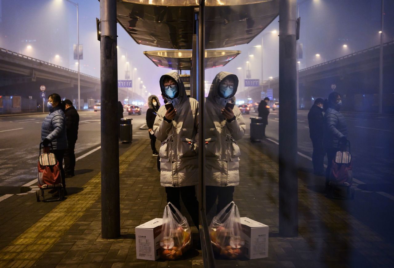 Chinese commuters?wear protective masks as they wait for a bus at a usually busy stop on February 13, in Beijing, China. 