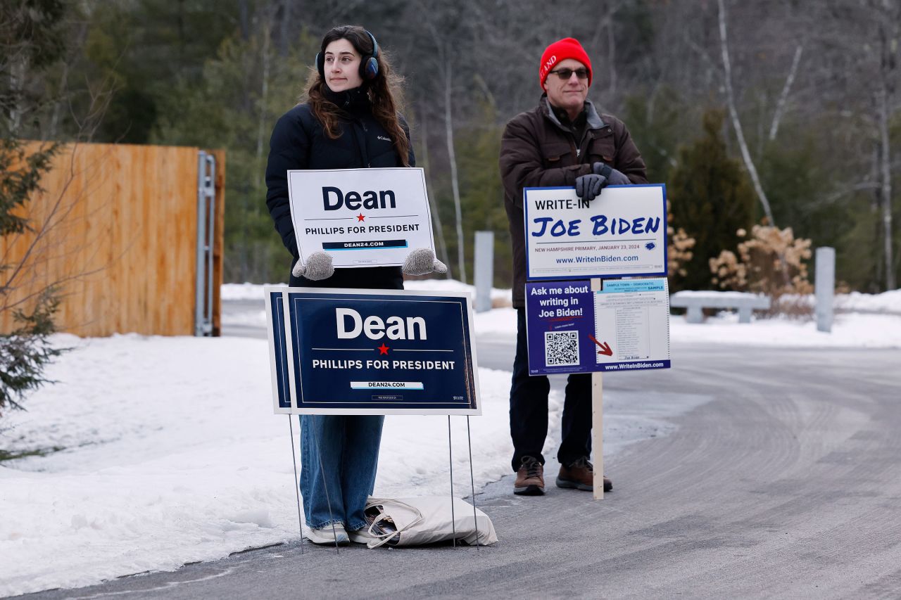 Mae Hougo, left, a volunteer for Rep. Dean Phillips, and Chuck Willing, a volunteer with the President Joe Biden write-in campaign, stand outside the polling place at The Barn at Bull Meadow during the New Hampshire presidential primary on January 23, in Concord, New Hampshire.