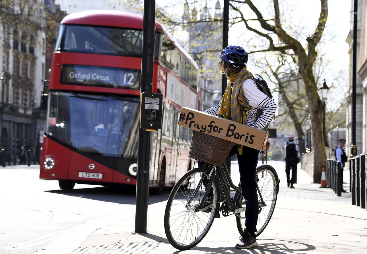 A woman on a bicycle displays a sign of support for British Prime Minister Boris Johnson, who remains in hospital in London, on April 7.