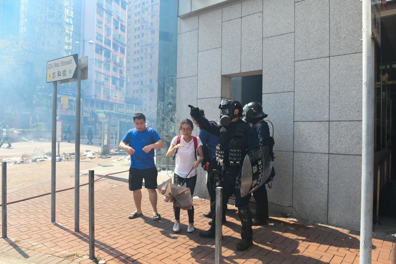 Police direct two bystanders in a haze of tear gas in Kowloon on Monday.