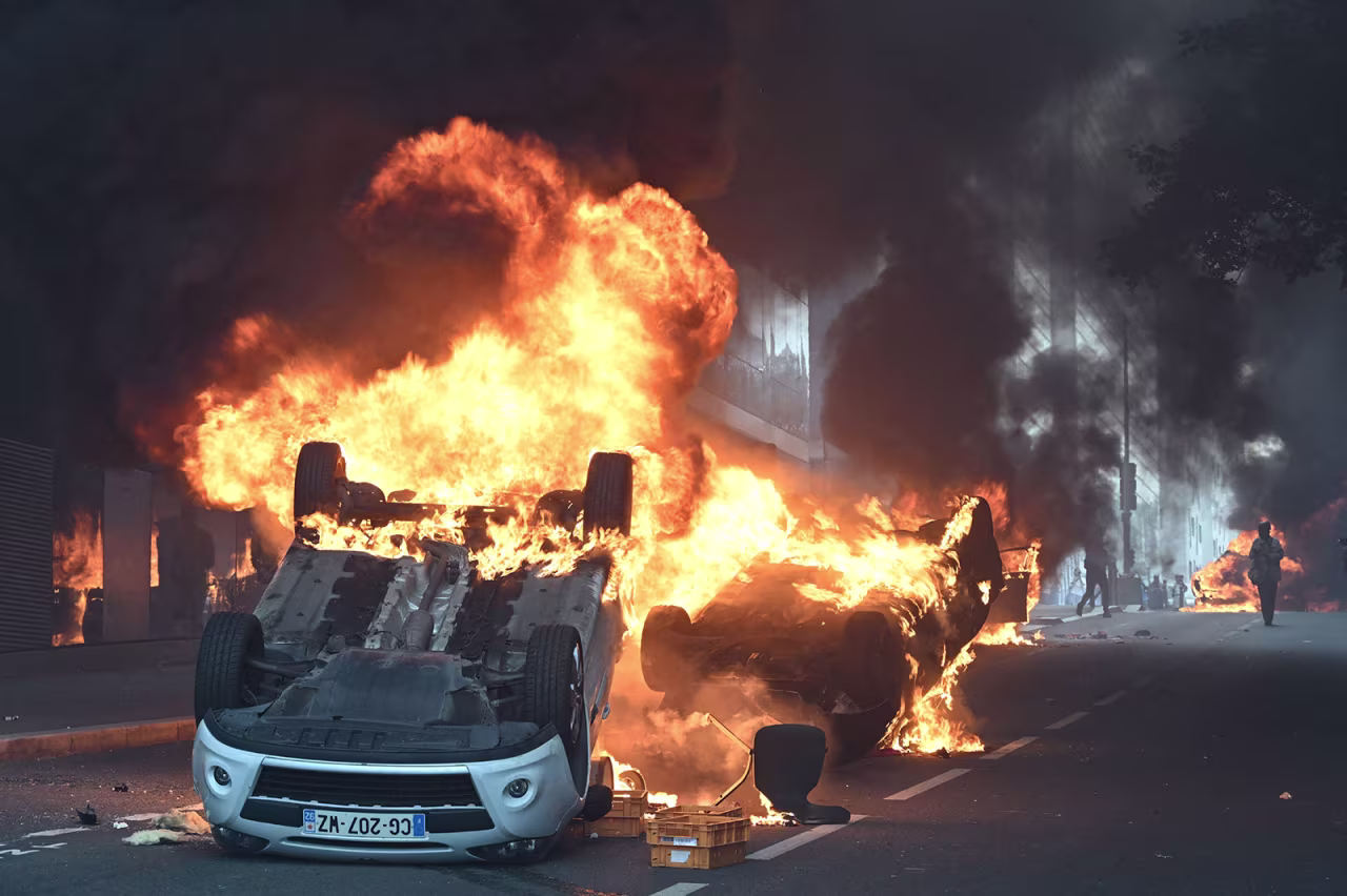 Vehicles burn in the street at the end of the march.