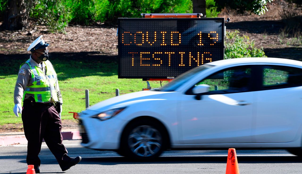 A traffic officer directs drivers as people arrive and depart from the Covid-19 testing venue at Dodger Stadium in Los Angeles, on Thursday, November 12.