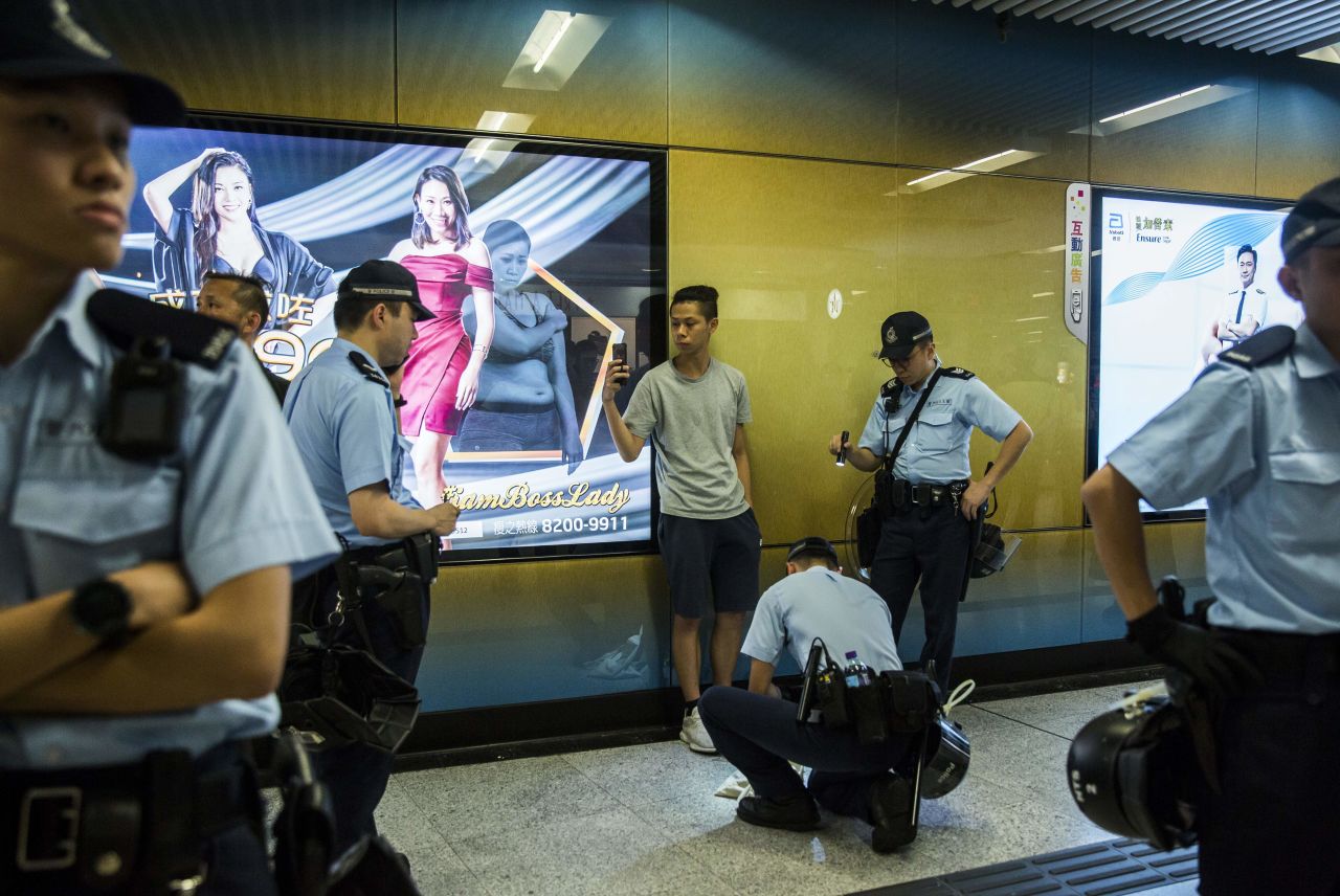 Police search a young commuter inside Admiralty MTR station.