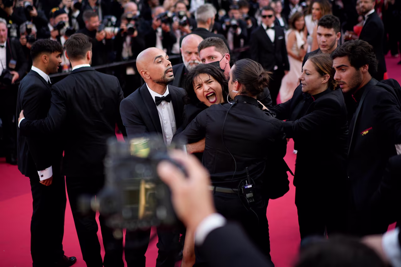 A protester wearing body paint that reads "Stop Raping Us" in the color of the Ukrainian flag is removed from the red carpet at the Cannes film festival in France on May 20.