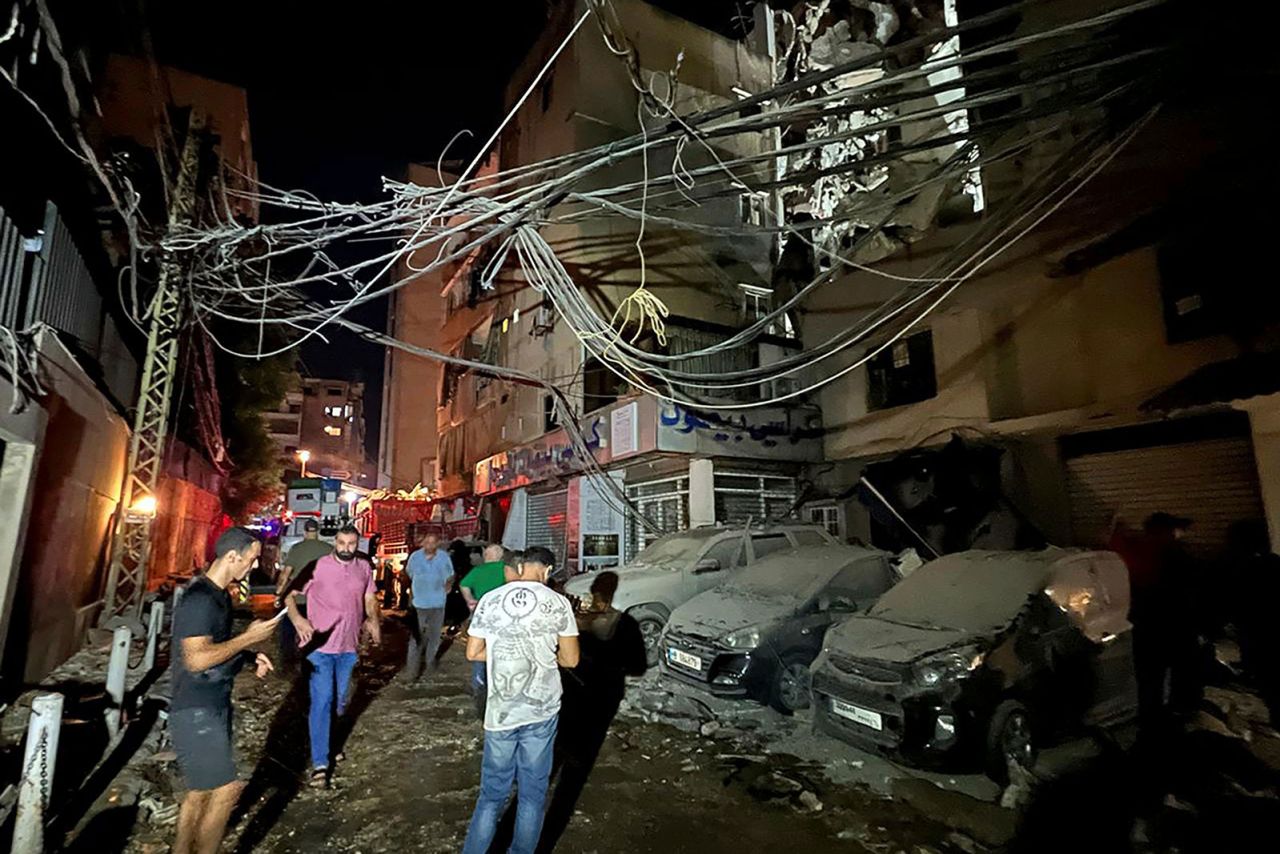 People gather near a destroyed building that was hit by an Israeli airstrike in the southern suburbs of Beirut, Lebanon, Tuesday, July 30.