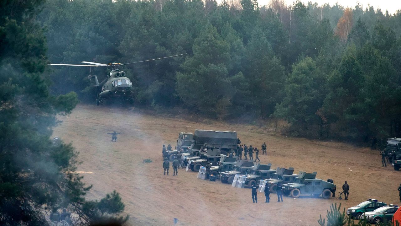 A Polish military helicopter lands next to troops near migrants gathering at the Belarus-Poland border near Grodno, Belarus, on Friday, November 12. 