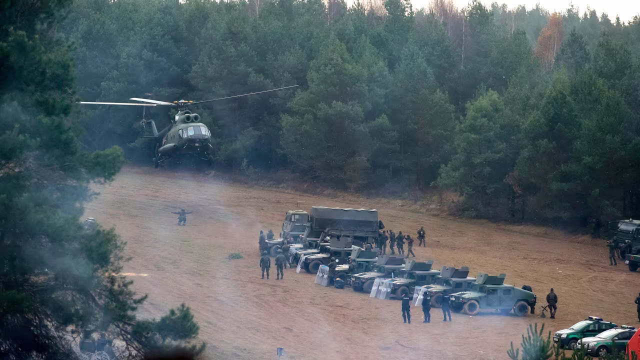 A Polish military helicopter lands next to troops near migrants gathering at the Belarus-Poland border near Grodno, Belarus, on Friday, November 12. 
