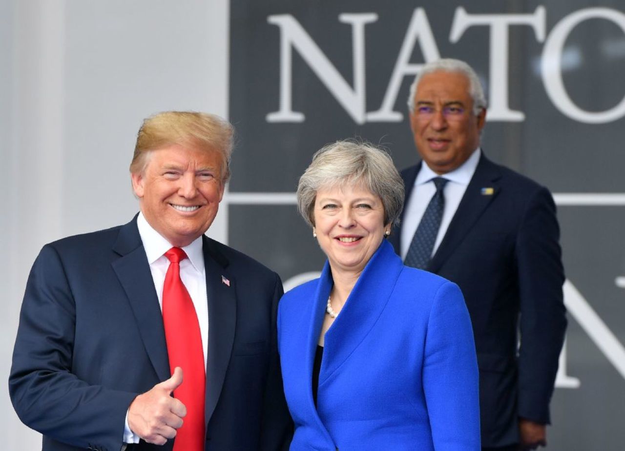 US President Donald Trump (L) gestures as he poses alongside Britain's Prime Minister Theresa May (R) as Portugal's Prime Minister Antonio Costa (TOP) looks on during the opening ceremony of the NATO in Brussels on July 11, 2018