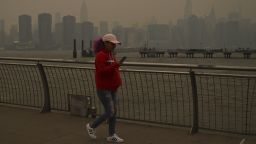 People walk along a pier in Transmitter Park as the Manhattan skyline is shrouded in smoke from Canada wildfires on June 6.