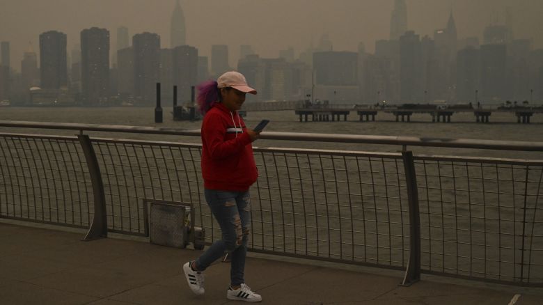 People walk along a pier in Transmitter Park as the Manhattan skyline is shrouded in smoke from Canada wildfires on June 6.