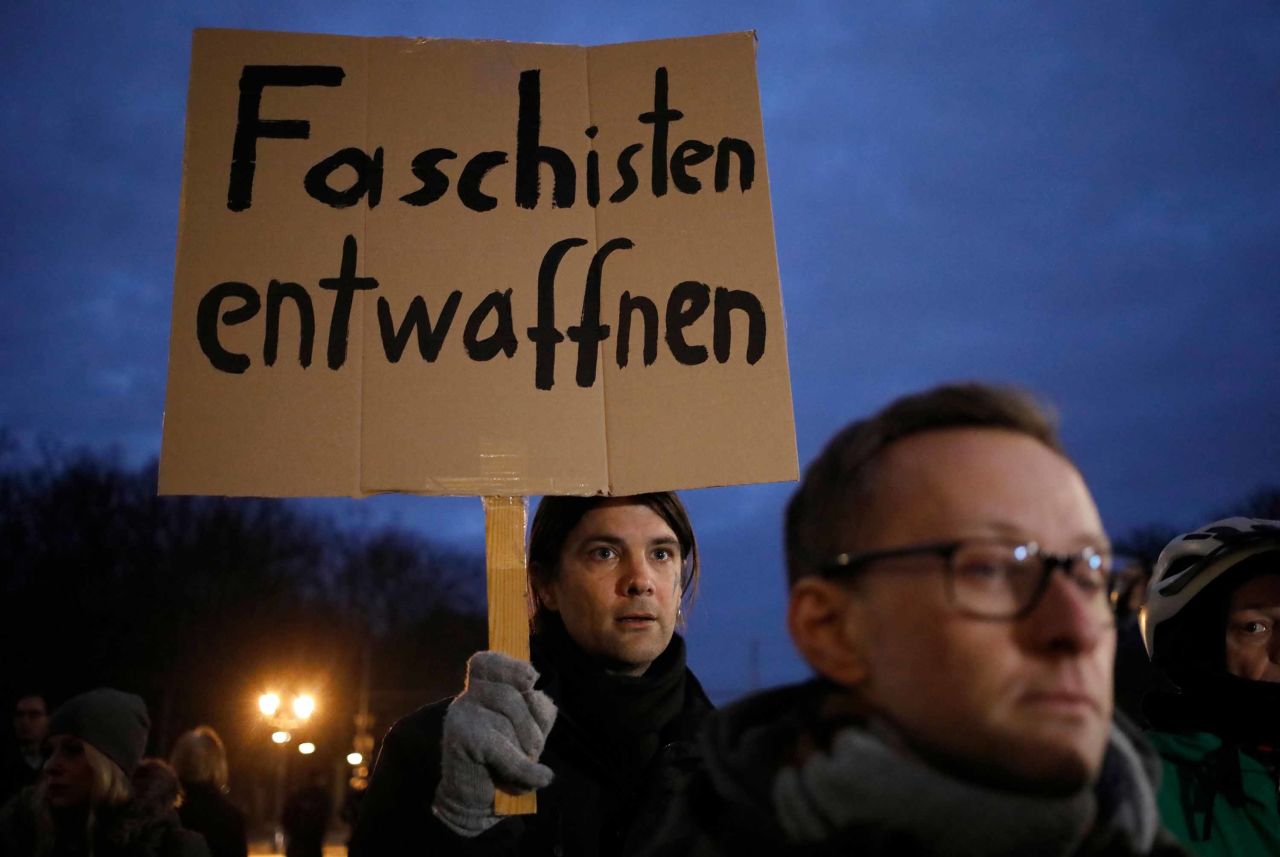 A man holds a poster reading "Disarm fascists" during the vigil at Brandenburg Gate.