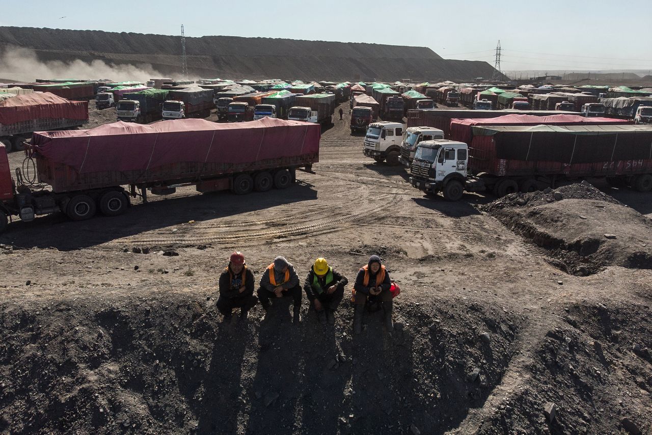 Workers sit in front of trucks loaded with coal at the Tavan Tolgoi coal deposit in Tsogtsetsii, Omnogovi province, Mongolia, on September 24, 2018. 