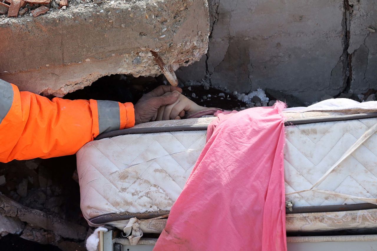 A closer view shows Hancer holding his daughter Irmak's hand amid the rubble. 