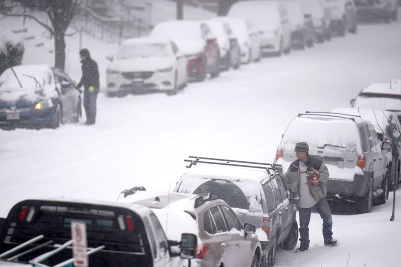 People clear snow off of cars Monday, February 15, in St. Louis. Missouri