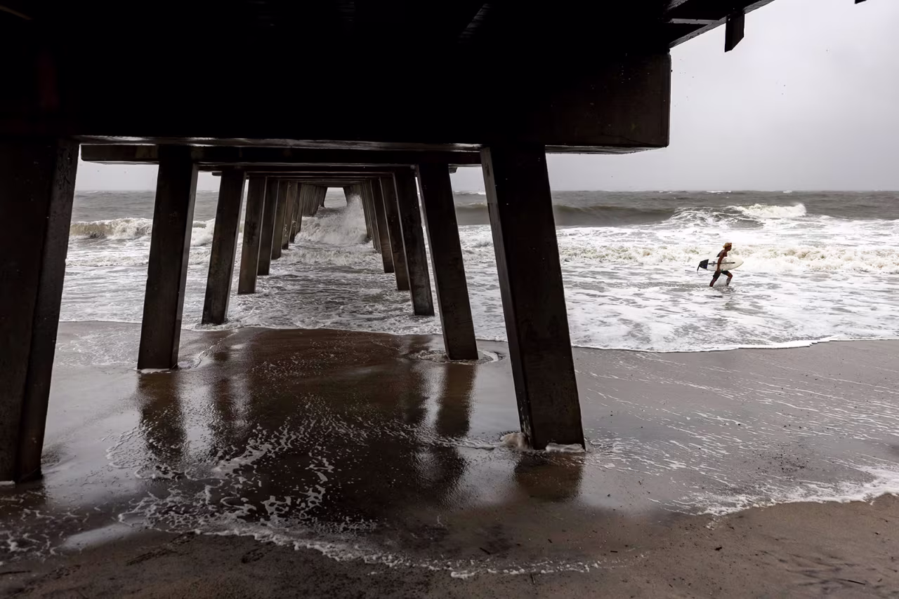 A surfer comes out of the water after riding the waves created by Tropical Storm Debby near the Tybee pier, in Tybee Island, Georgia, August 6. 